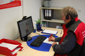 Foto: ein Mann in Dienstkleidung sitzt während einer Online-Beratung vor einem Computermonitor